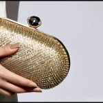 여성용 파티백 스타일 - **Prompt 1: "Golden Glamour Clutch"**
    A chic woman, mid-20s to 30s, dressed in a flowing, elegan...